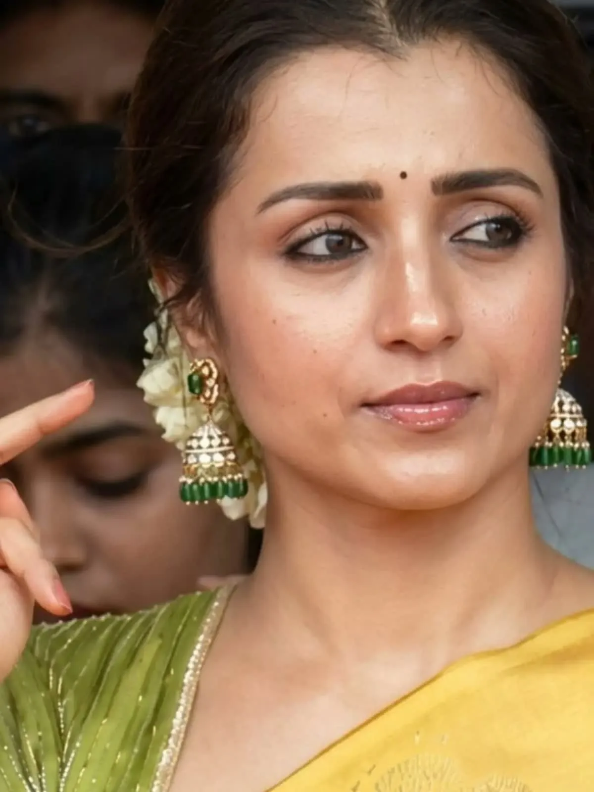 Trisha Krishnan — The jhumka in full: green stone stud, white kundan dome, green bead fringe, against the jasmine