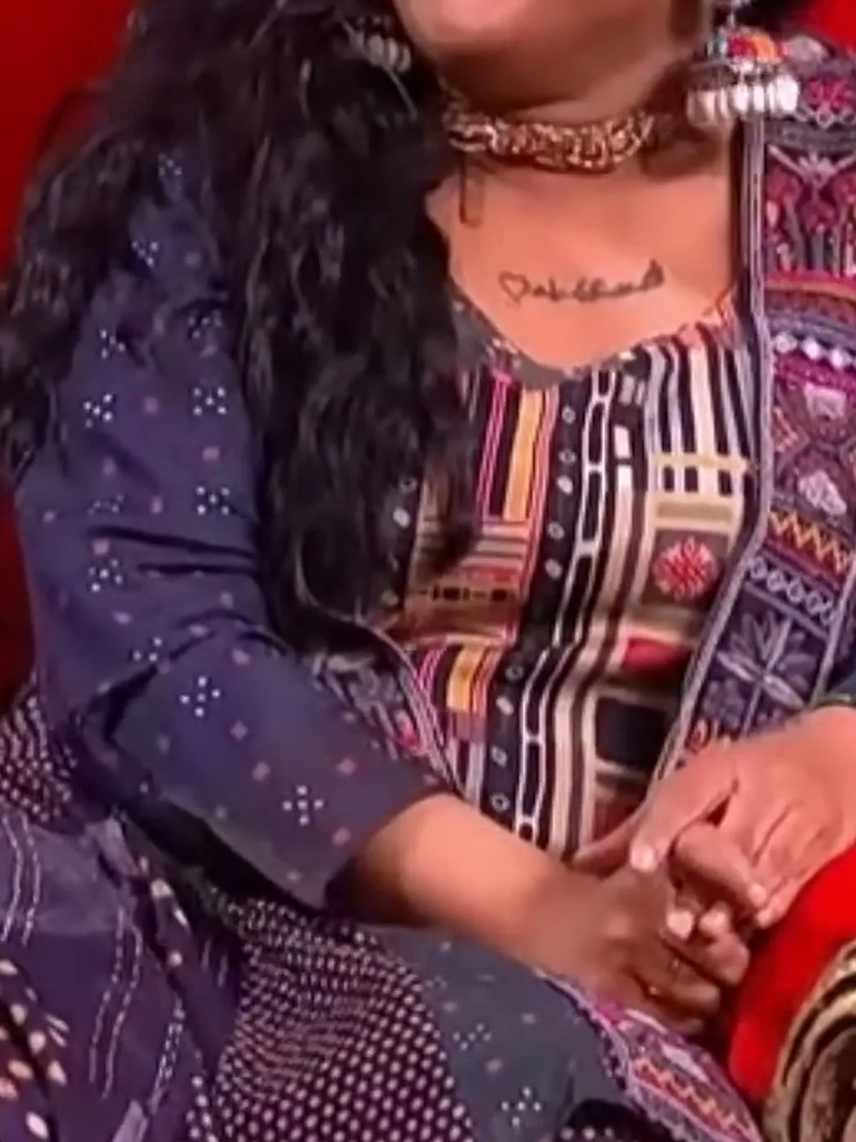 Vanitha Vijayakumar — Close on the front band: silver braid, then magenta and coral temple figures, with teal-green behind them