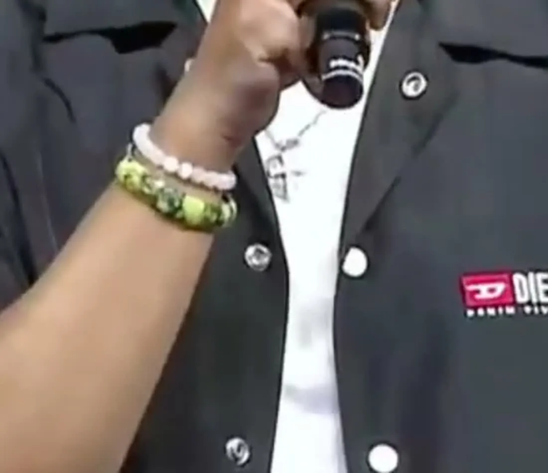 Jason Sanjay — The wrist at full resolution: green stone beads below, pale pink above, and the thin gold cross chain