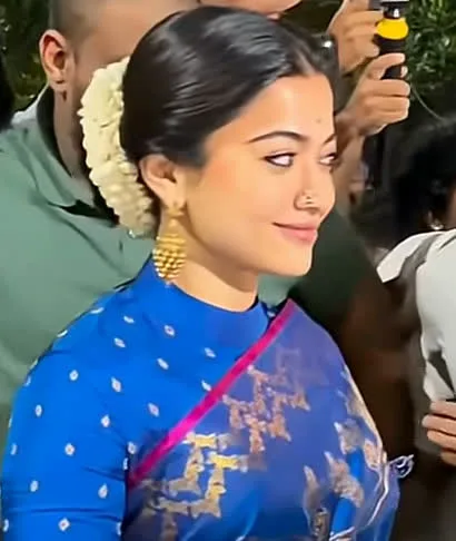 Rashmika Mandanna — Arriving outside: jasmine in the bun, gold at the ears, the pink edge over the shoulder