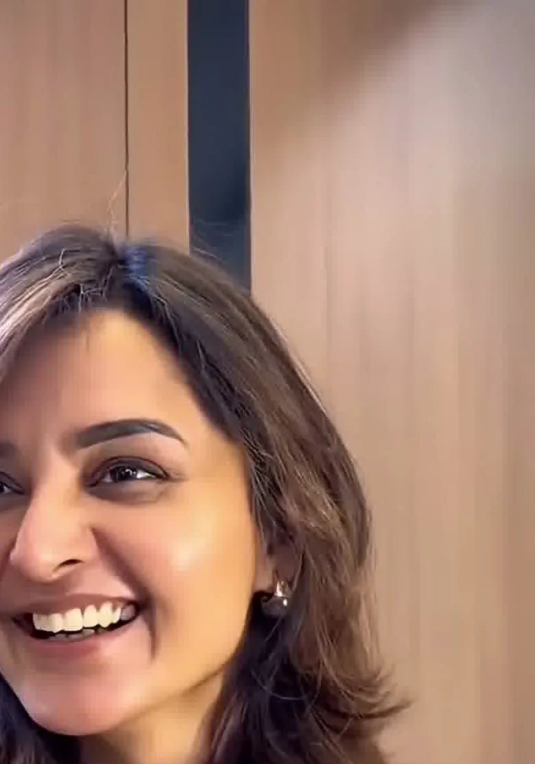 Manju Warrier — Turned three-quarters, mid-laugh — the dropped shoulder line the shoulder pads create